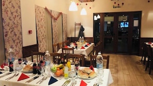 Un espace repas avec des tables dressées pour les repas, des chaises et une variété d’articles de vaisselle.