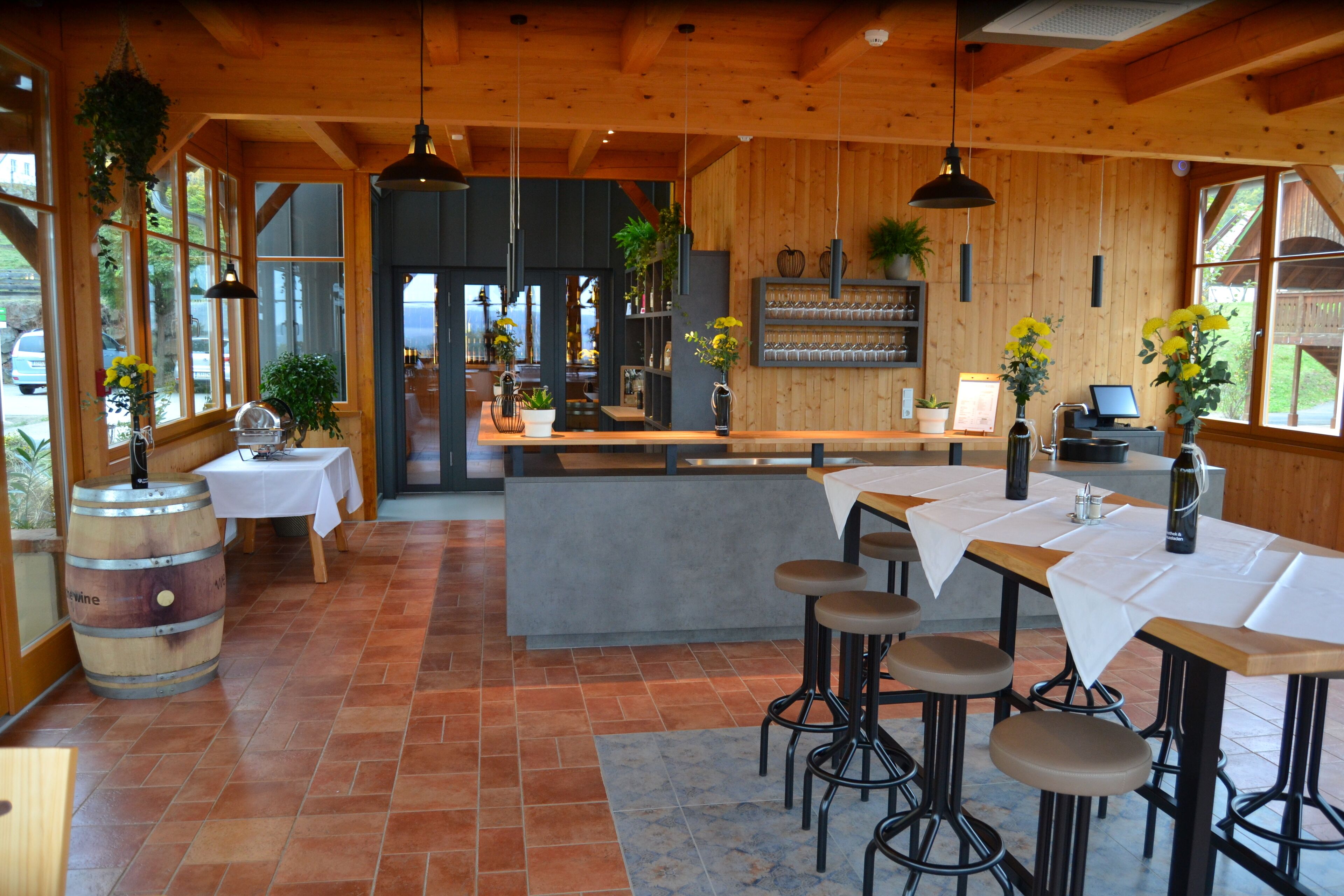 Un ristorante con arredi in legno, diversi tavoli, sgabelli da bar e piante pensili.