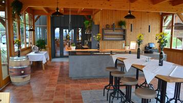 Un ristorante con arredi in legno, diversi tavoli, sgabelli da bar e piante pensili.