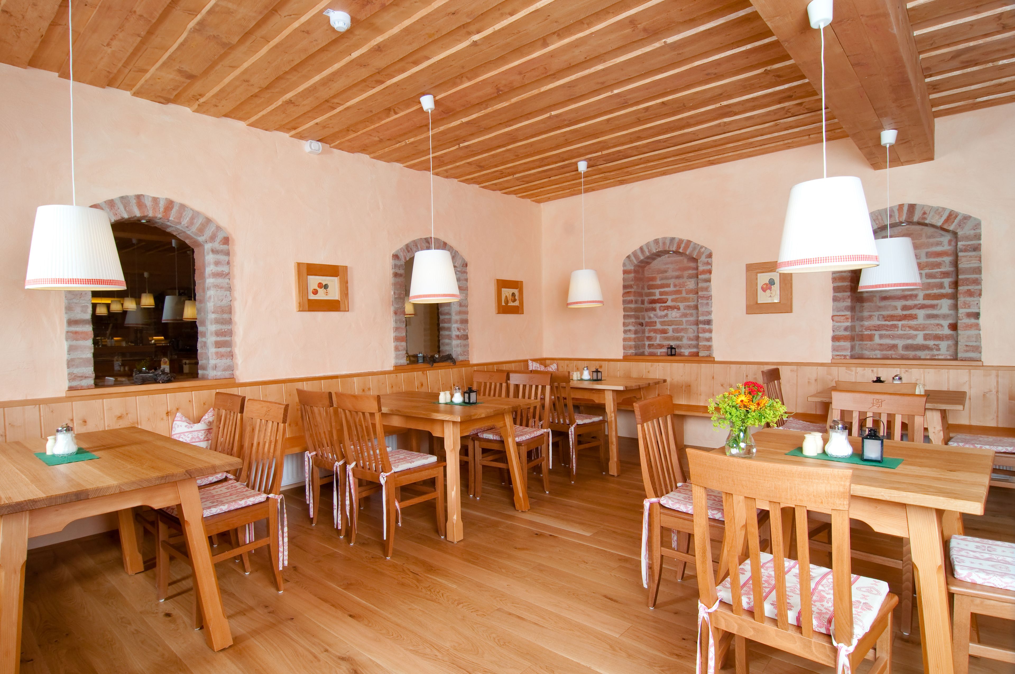 Ein Restaurant mit Holztischen und -stühlen, Ziegelbogen und hängenden Pendelleuchten.