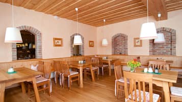 Ein Restaurant mit Holztischen und -stühlen, Ziegelbogen und hängenden Pendelleuchten.