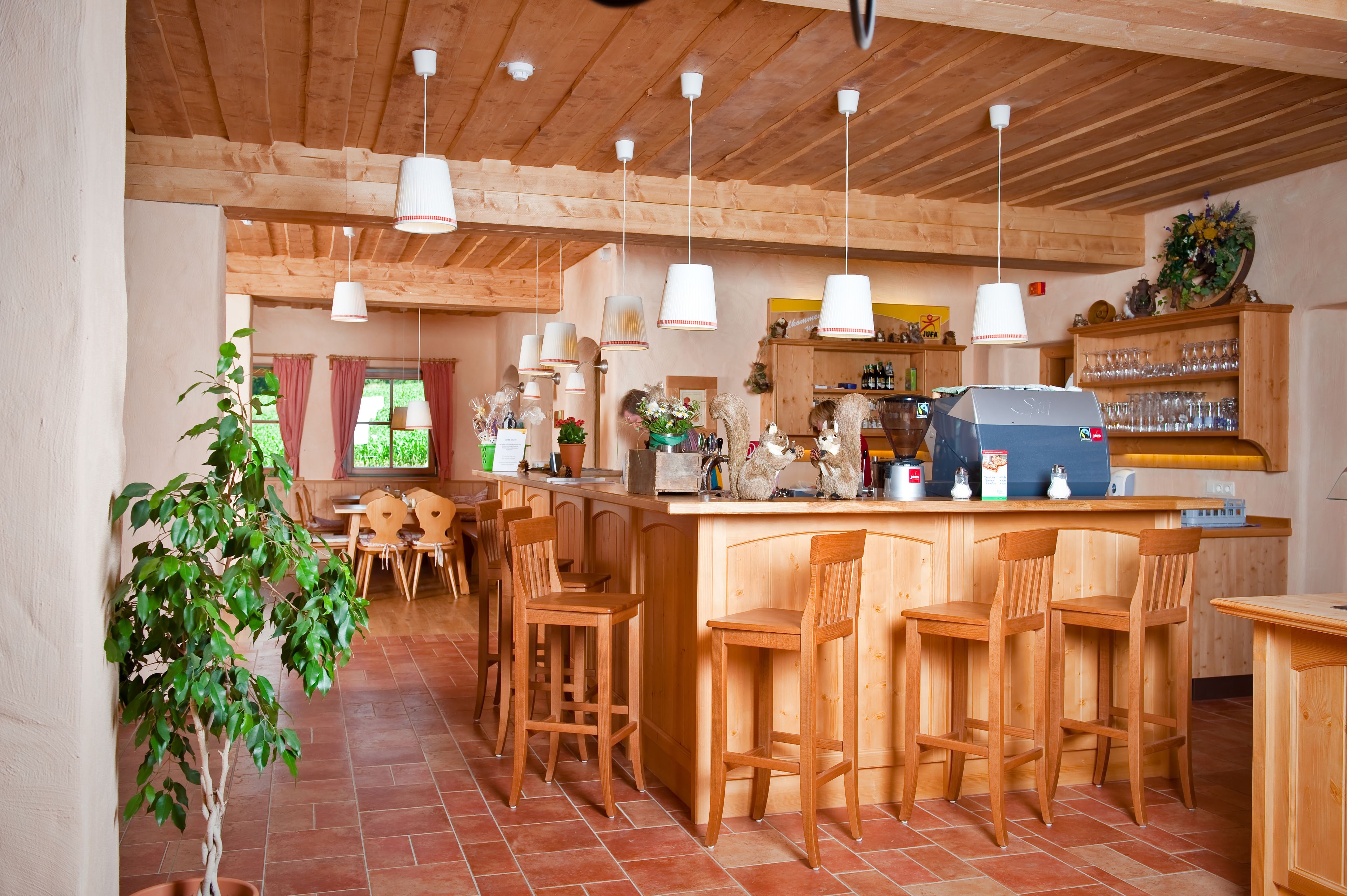 Een houten interieur met een bar, houten stoelen en een potplant.