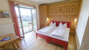 Un dormitorio con cama doble, cabecera de madera y puerta corrediza de vidrio que da a un balcón.