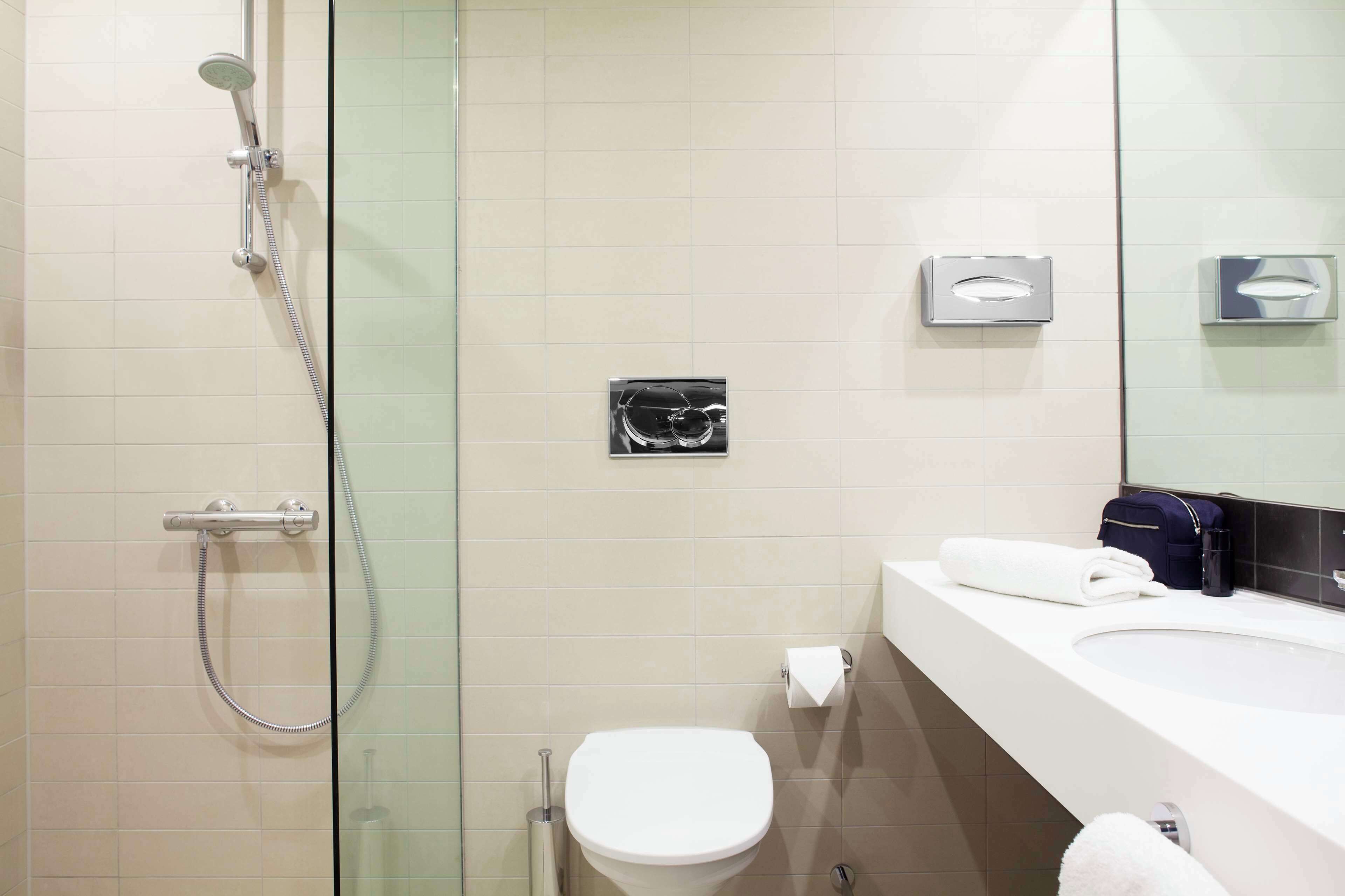 A modern bathroom with a glass-enclosed shower, a white toilet, and a sink with a towel.