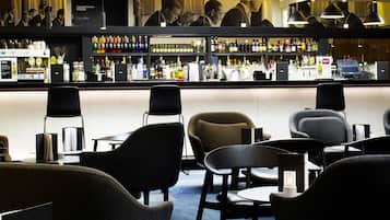 A bar area with seating, a counter with various bottles, and overhead lighting.