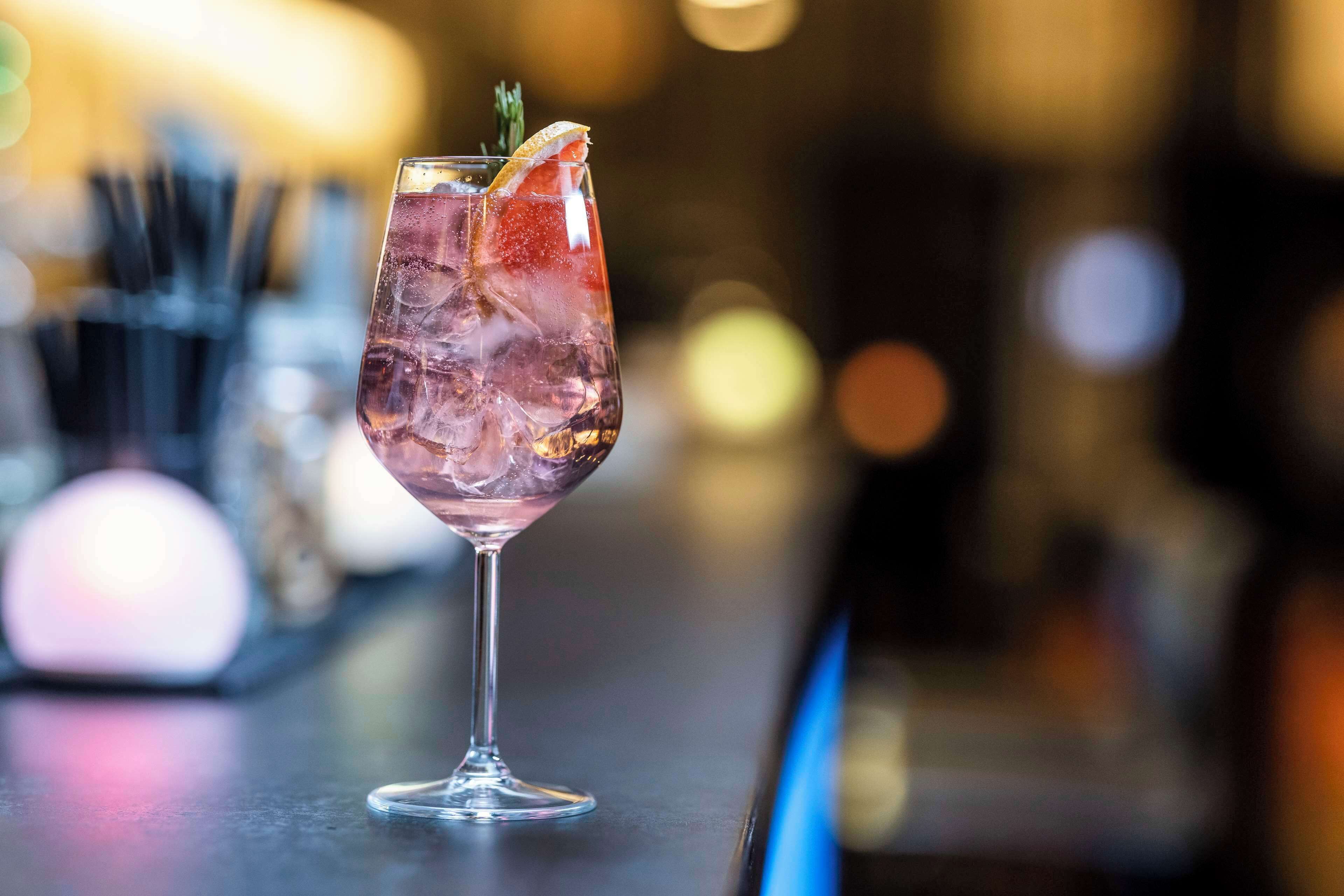 A cocktail glass with ice cubes and a garnish on a bar counter.