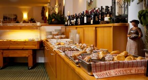 A buffet with various baked goods and a selection of wine bottles. - Christophs Hotel (Schenna)