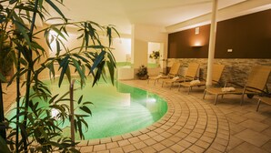 A spa area with a curved pool, lounge chairs, and bamboo plants. - Christophs Hotel (Schenna)