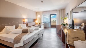 A hotel room with a bed, desk, chair, lamp, and a view of the outdoors. - Christophs Hotel (Schenna)