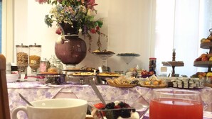 A buffet table with various food items, a vase with flowers, and a glass of red drink. - Hotel Julia (Comacchio)