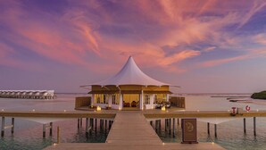 A resort with a large white pavilion, a wooden deck, and a view of the ocean. - Cinnamon Hakuraa Huraa Maldives - All Inclusive Adults-Only (Hakuraa Huraa)