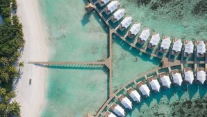 An aerial view of a resort with overwater bungalows arranged in a crescent shape, connected by a central walkway. - Cinnamon Hakuraa Huraa Maldives - All Inclusive Adults-Only (Hakuraa Huraa)