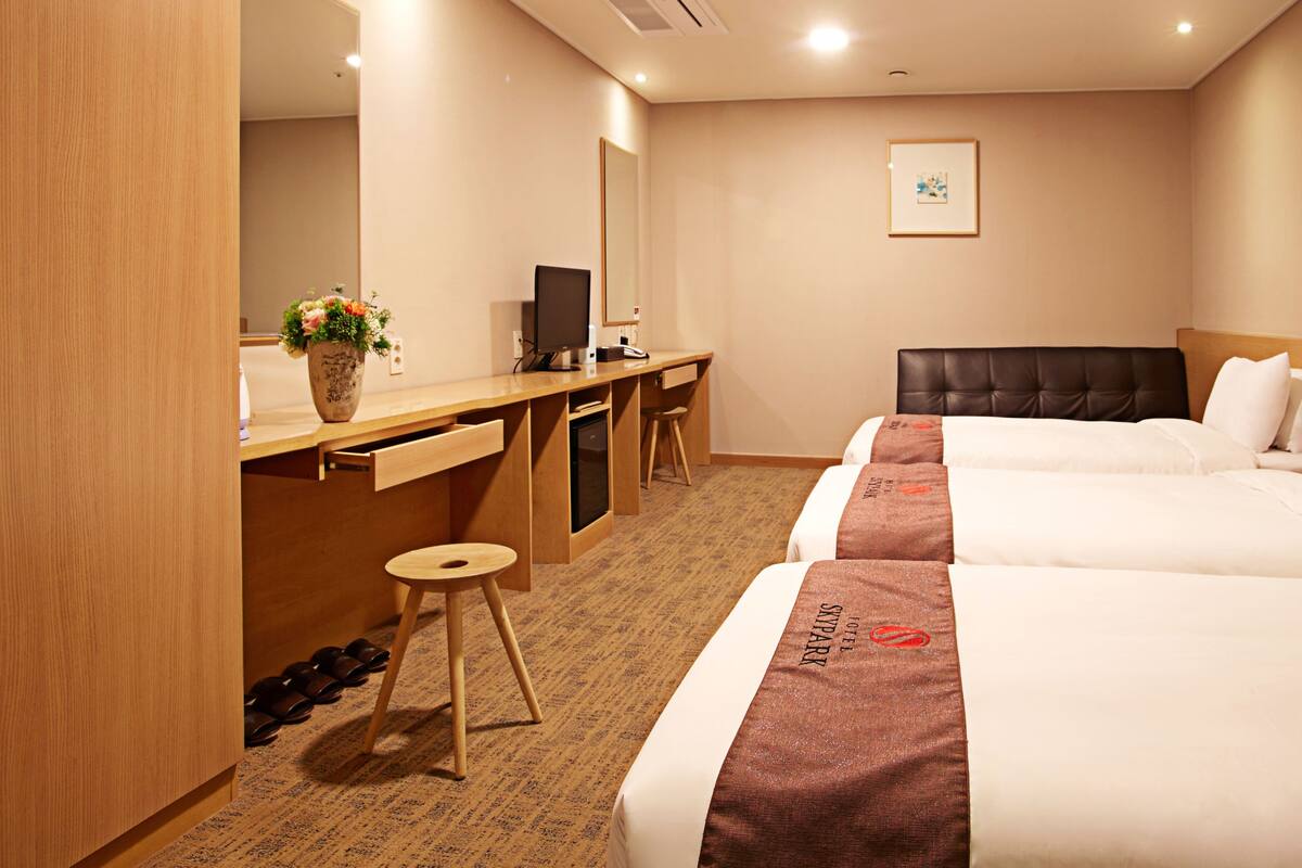 A hotel room with a bed, a desk, a chair, and a wardrobe.