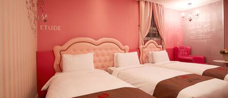 Habitación de hotel con dos camas, paredes rosadas y una silla roja.