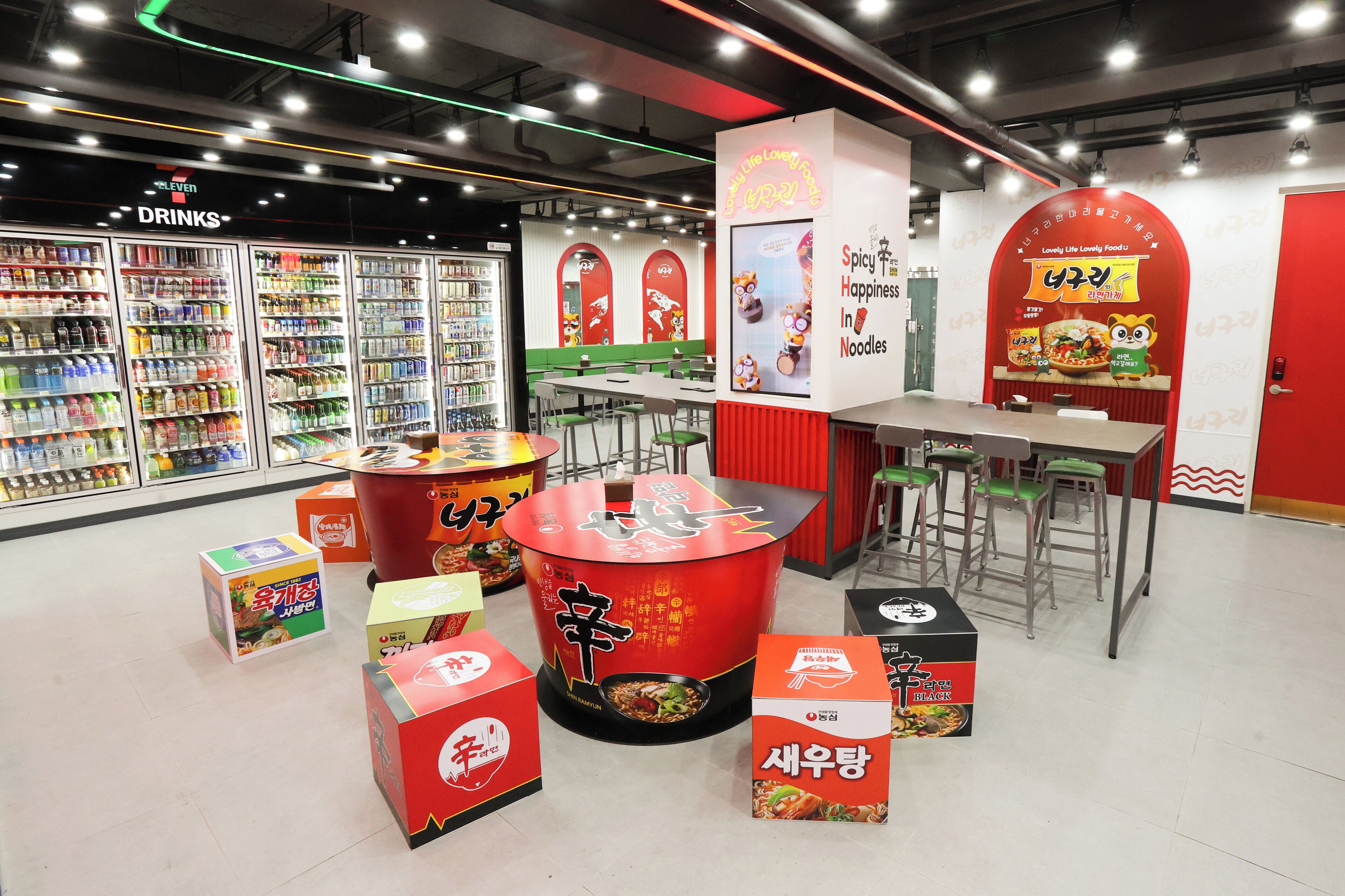 A food court with various food stalls, seating areas, and a beverage refrigerator.
