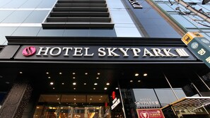 The entrance to Hotel Skypark III with a modern design, featuring a prominent sign and a series of lights above the entrance.