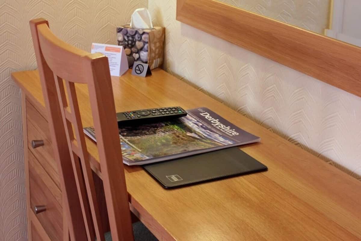 A wooden desk with a laptop, a magazine, and a tissue box.