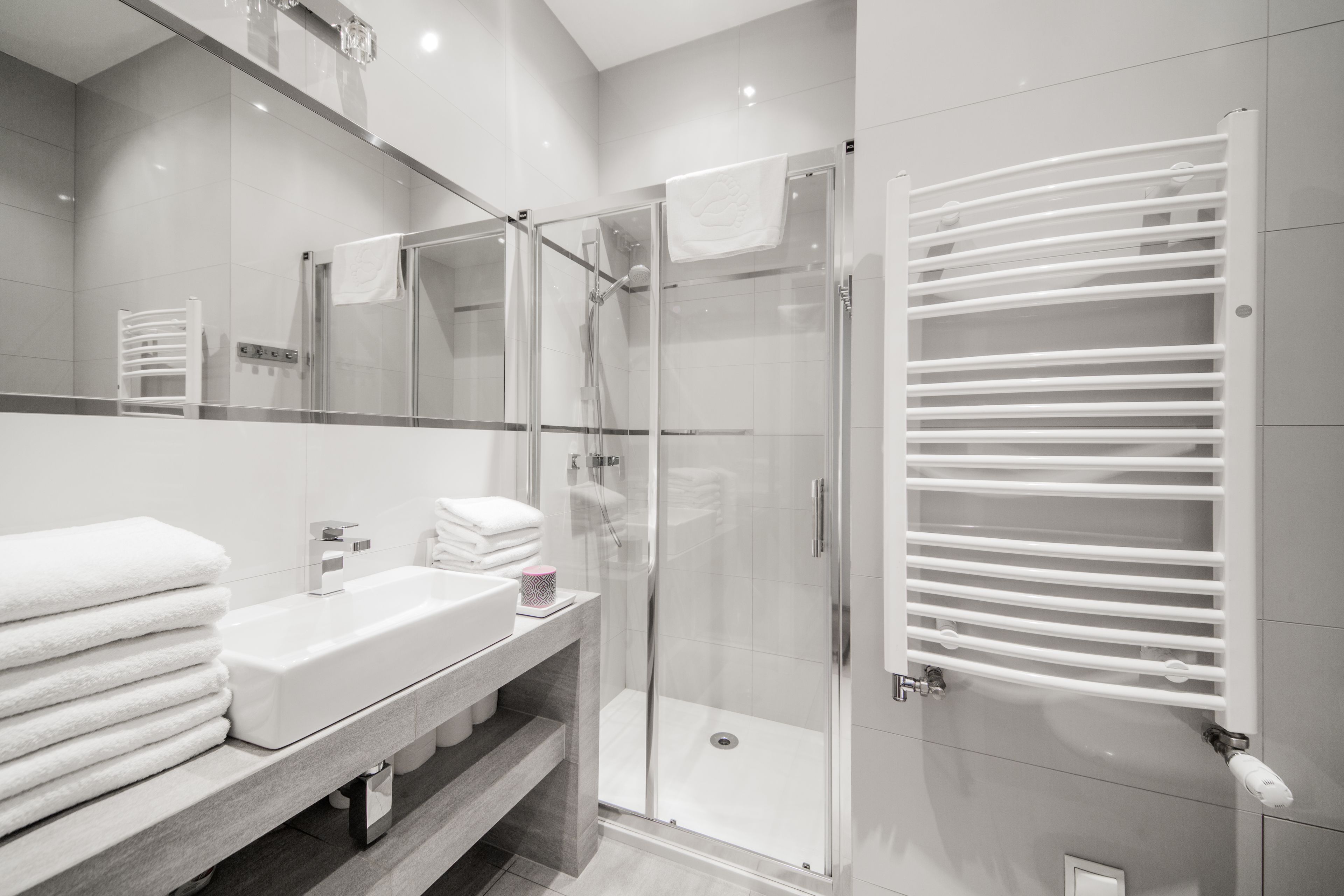 Un baño moderno con ducha envuelta en vidrio, un lavabo blanco y un perchero para toallas.