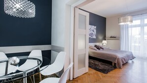 Un dormitorio moderno con cama, mesita de noche y una mesa de vidrio con sillas.