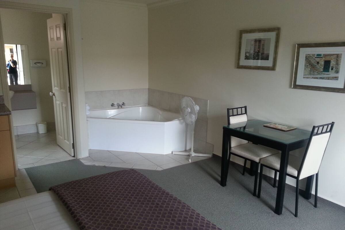 A bathroom with a bathtub, a fan, and a table with chairs.
