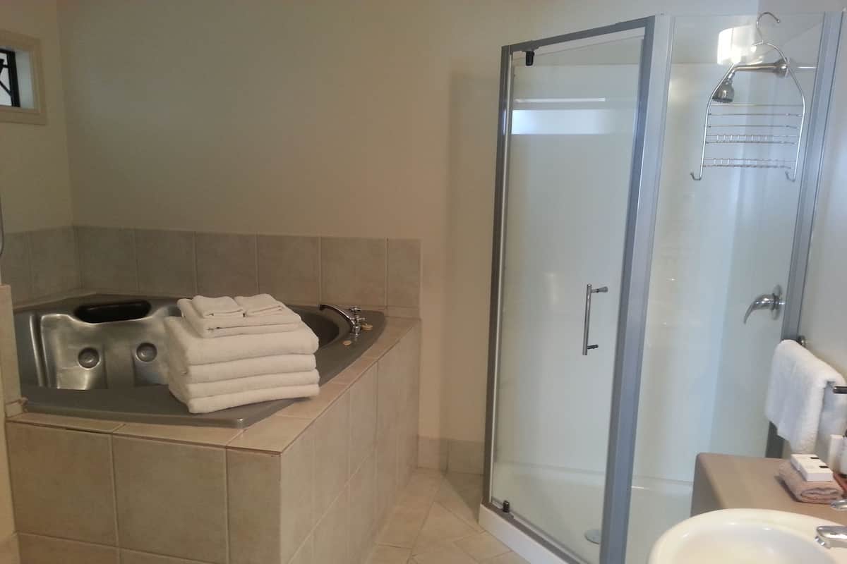 A modern bathroom with a glass-enclosed shower, a built-in sink, and a bathtub with stacked towels.