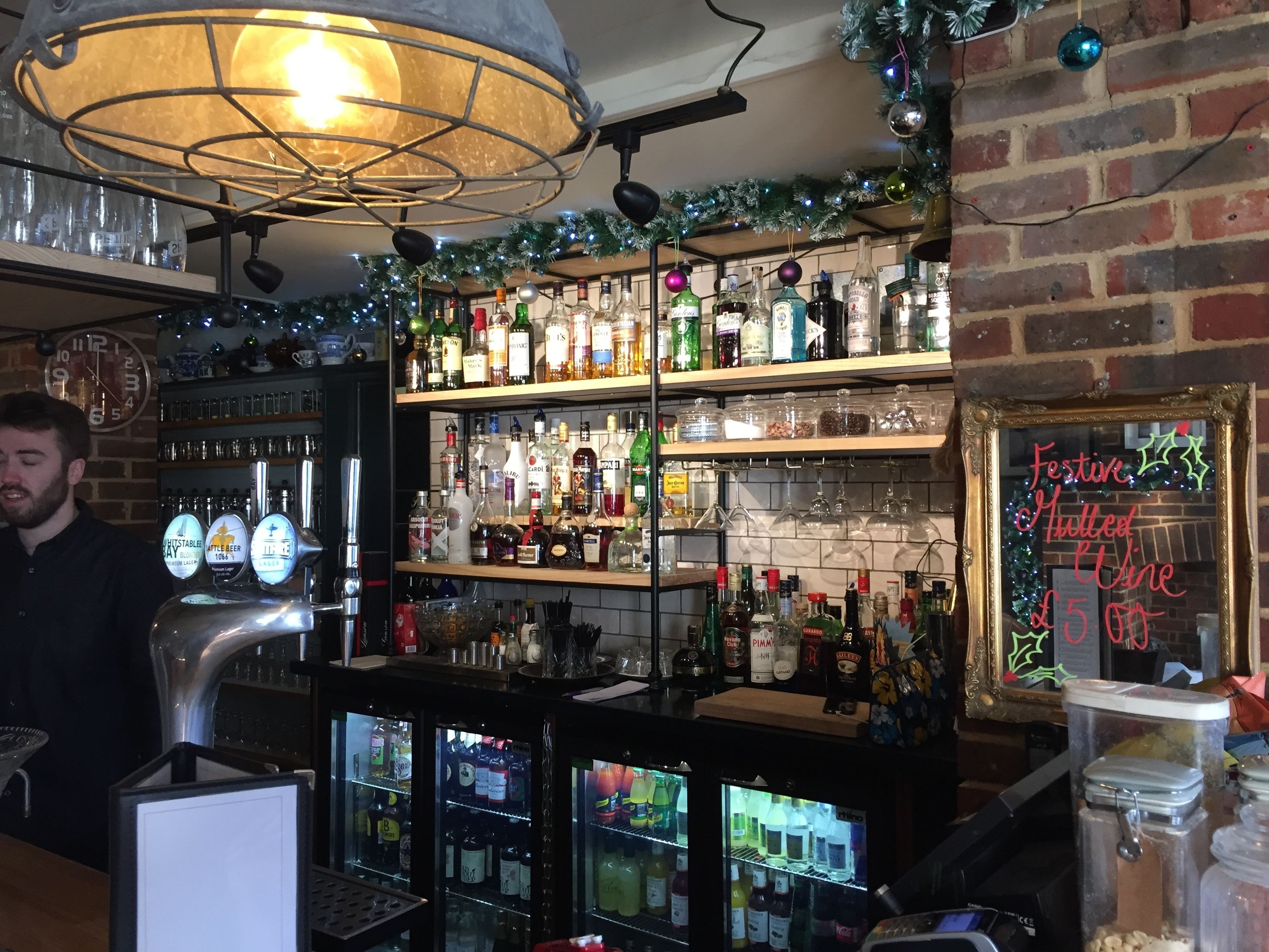 Uma área de bar com prateleiras de garrafas de bebidas, uma torneira de cerveja e um caixa.