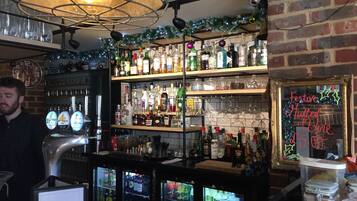 Uma área de bar com prateleiras de garrafas de bebidas, uma torneira de cerveja e um caixa.