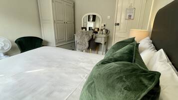 A hotel room with a bed, a desk, a chair, a mirror, and a wardrobe.