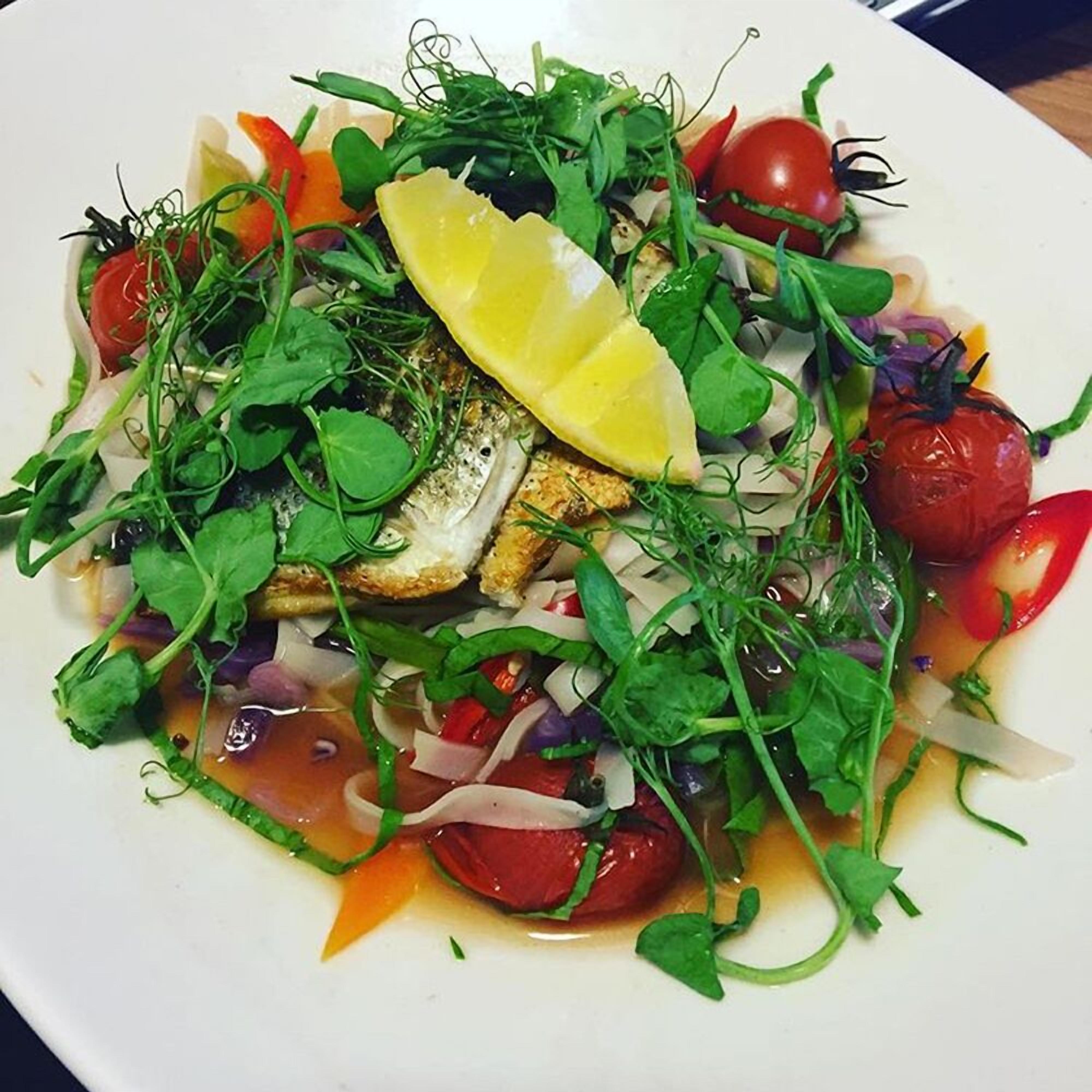 A plate of food with various vegetables and a lemon slice.
