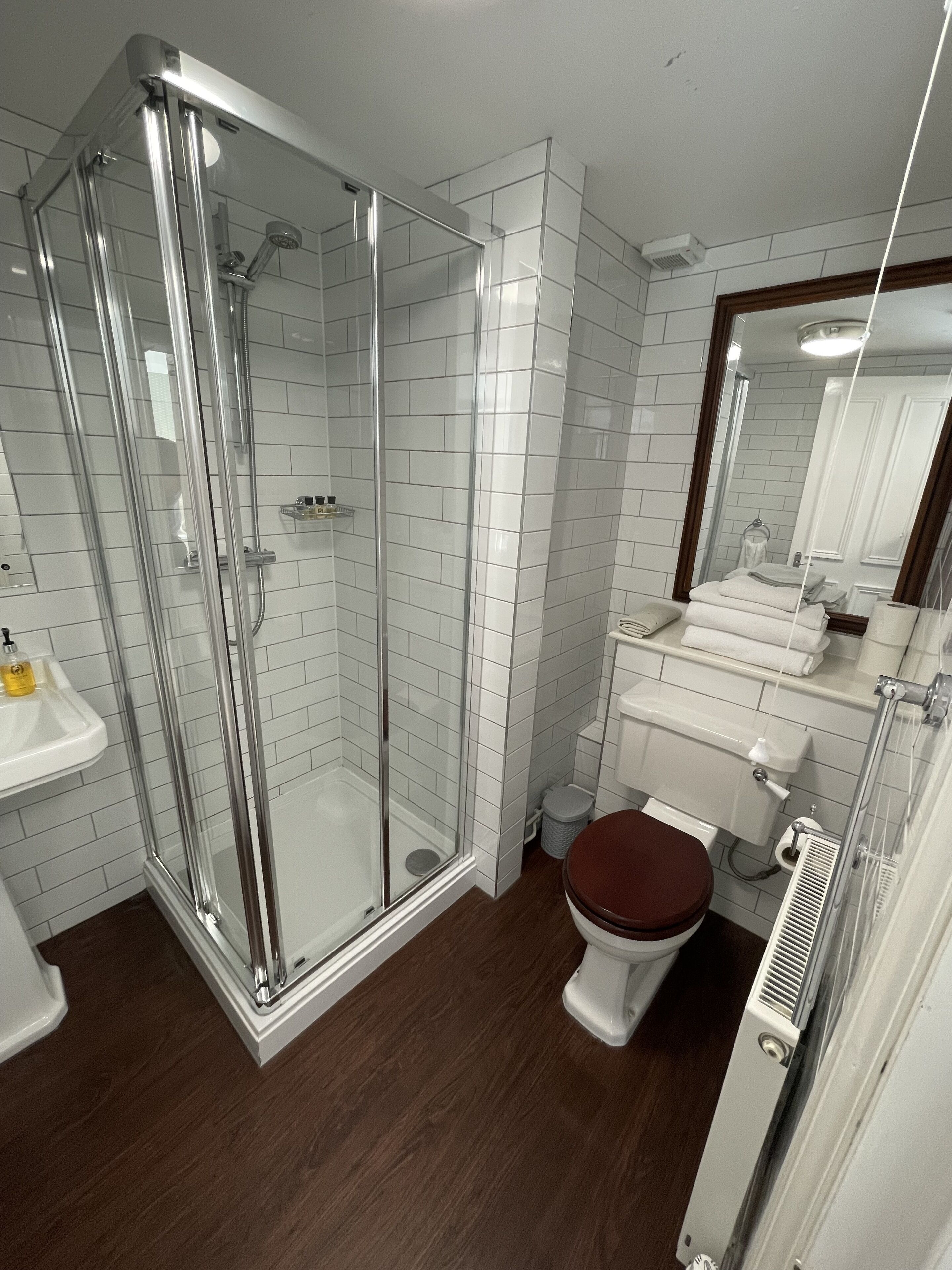 Un bany modern amb dutxa envidriada, un lavabo blanc i un vàter.