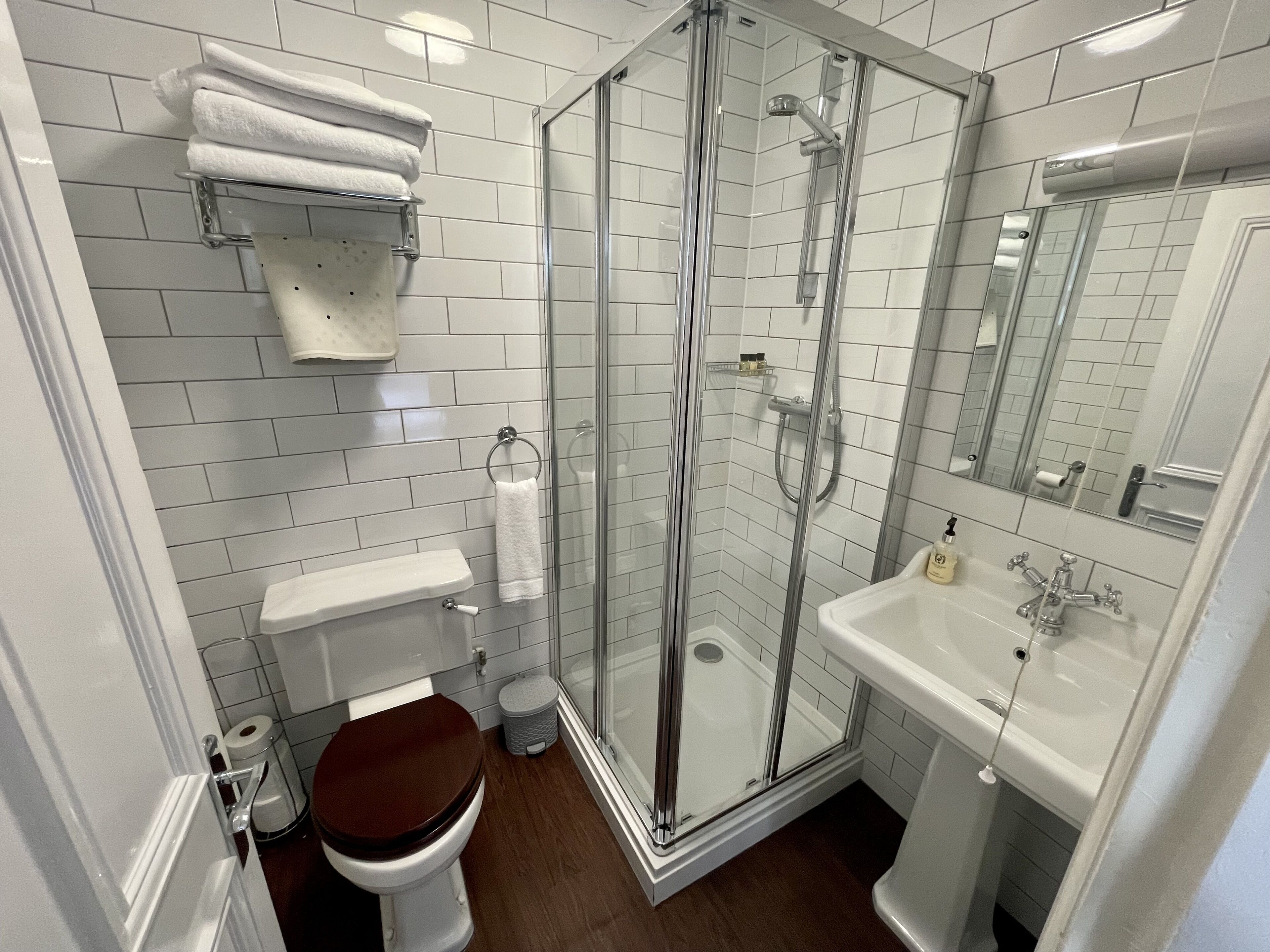 Ein modernes Badezimmer mit einer gläsernen Duschkabine, weißen Fliesen, einem Waschbecken und einer Toilette.