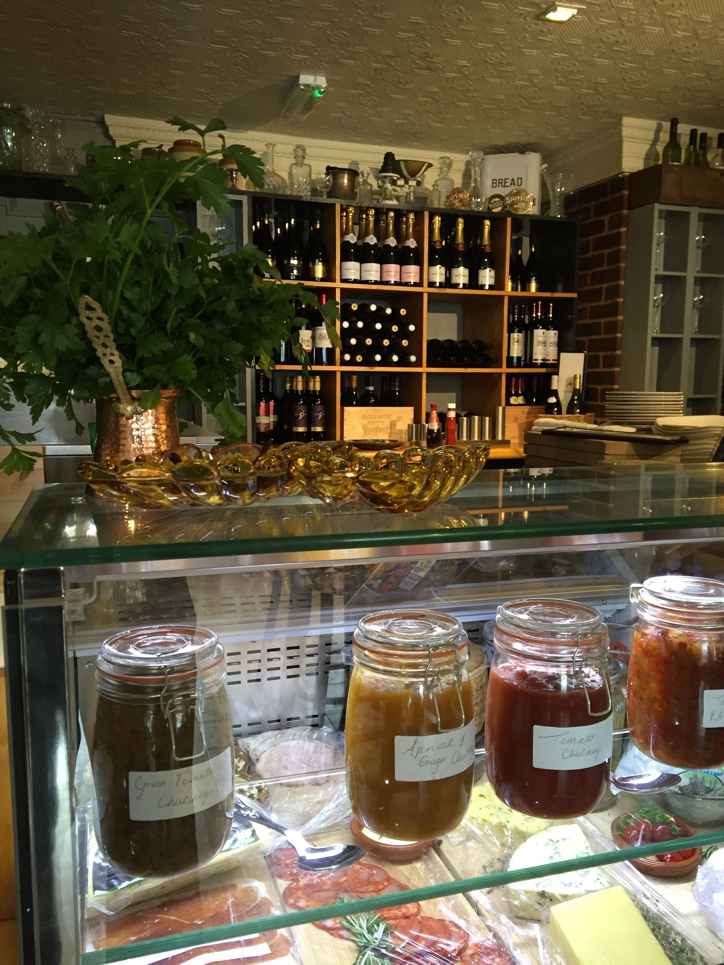 A deli counter with various food items and a wine shelf in the background.