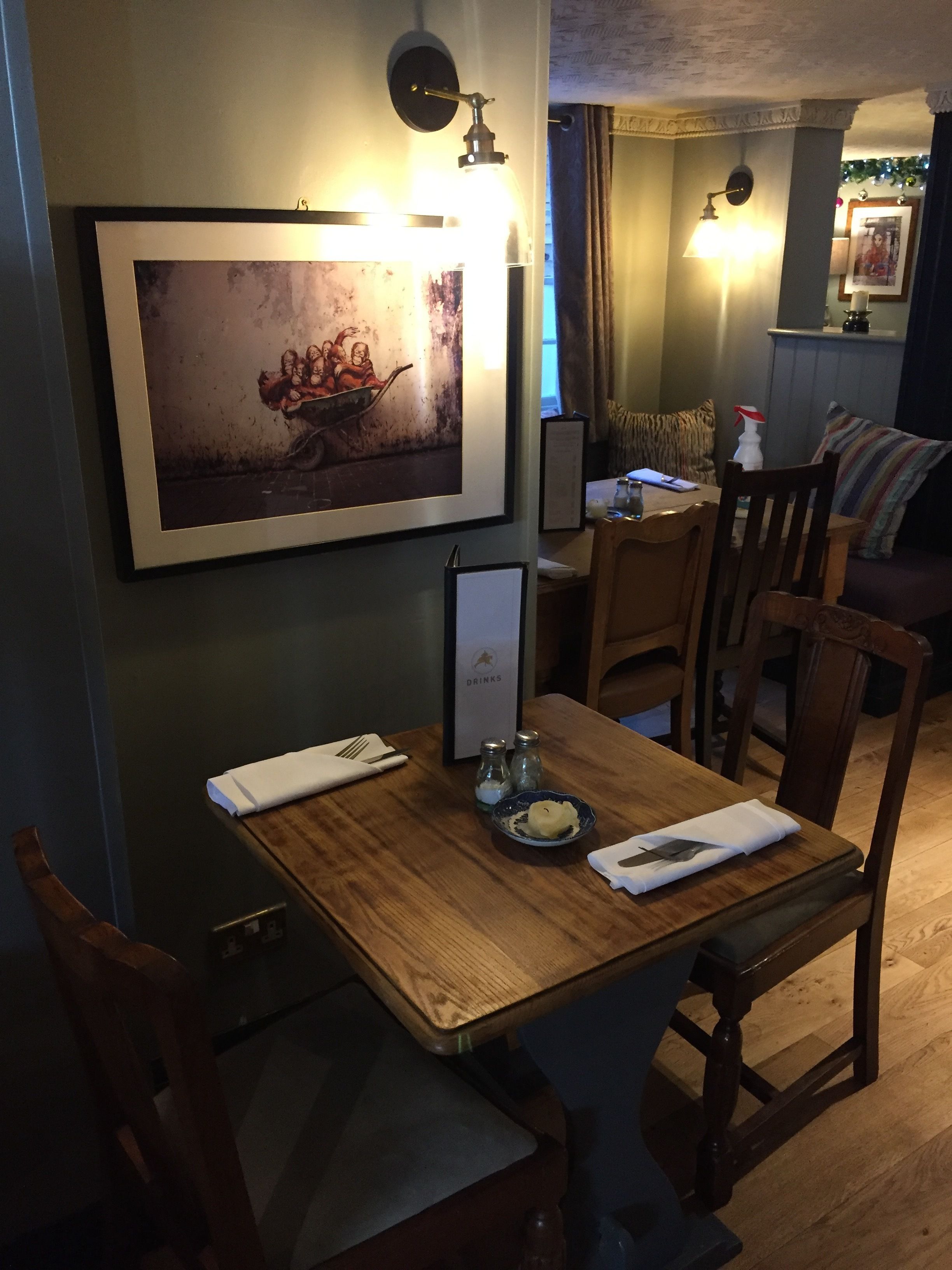 A dining area with a wooden table, chairs, a framed artwork, and a menu stand.