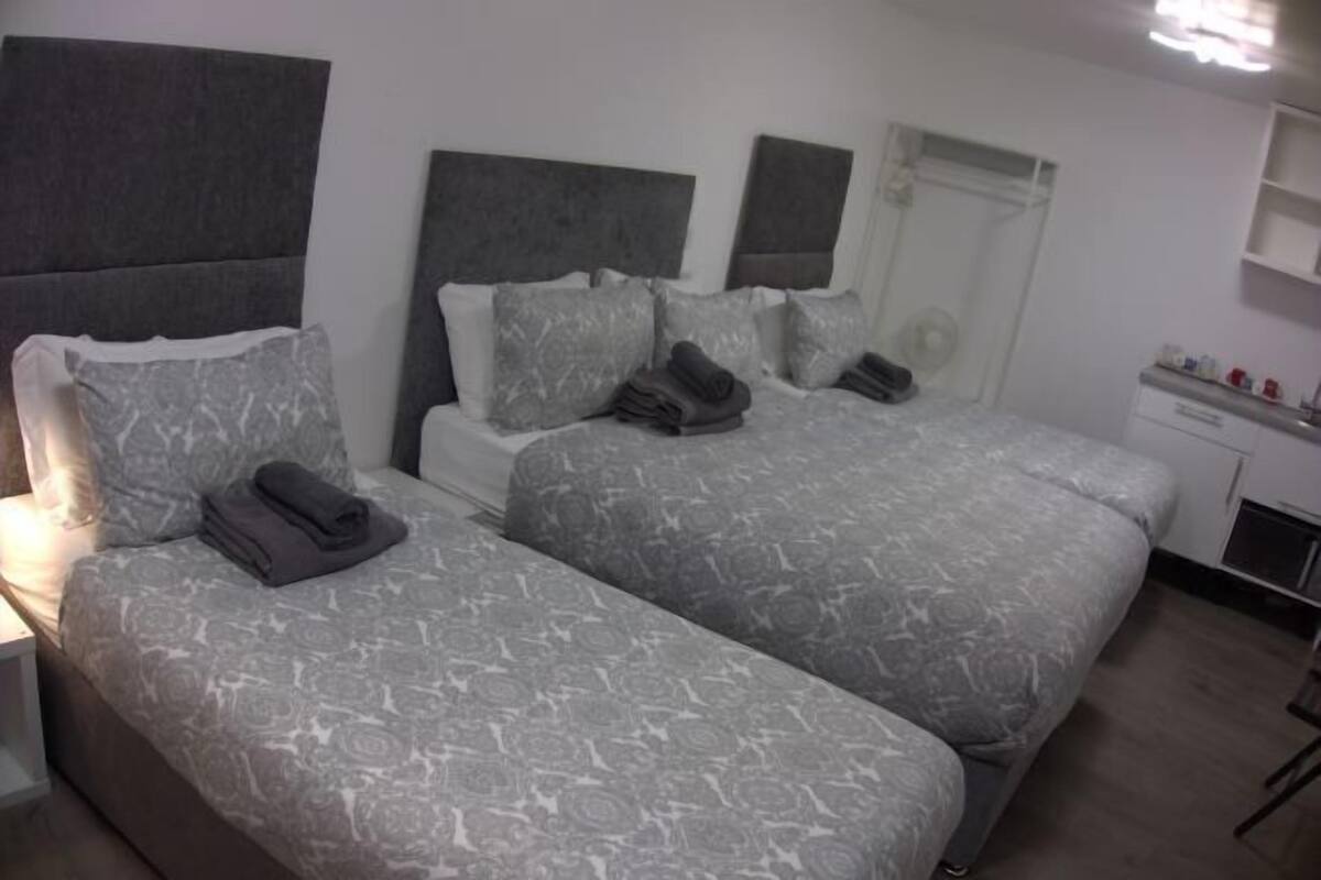 A hotel room with two beds, a bedside table, a wardrobe, and a mirror.