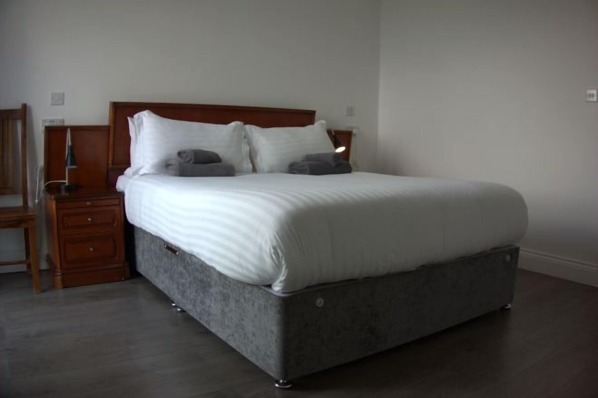 Un dormitorio con cama, mesitas de noche de madera y un aparador.