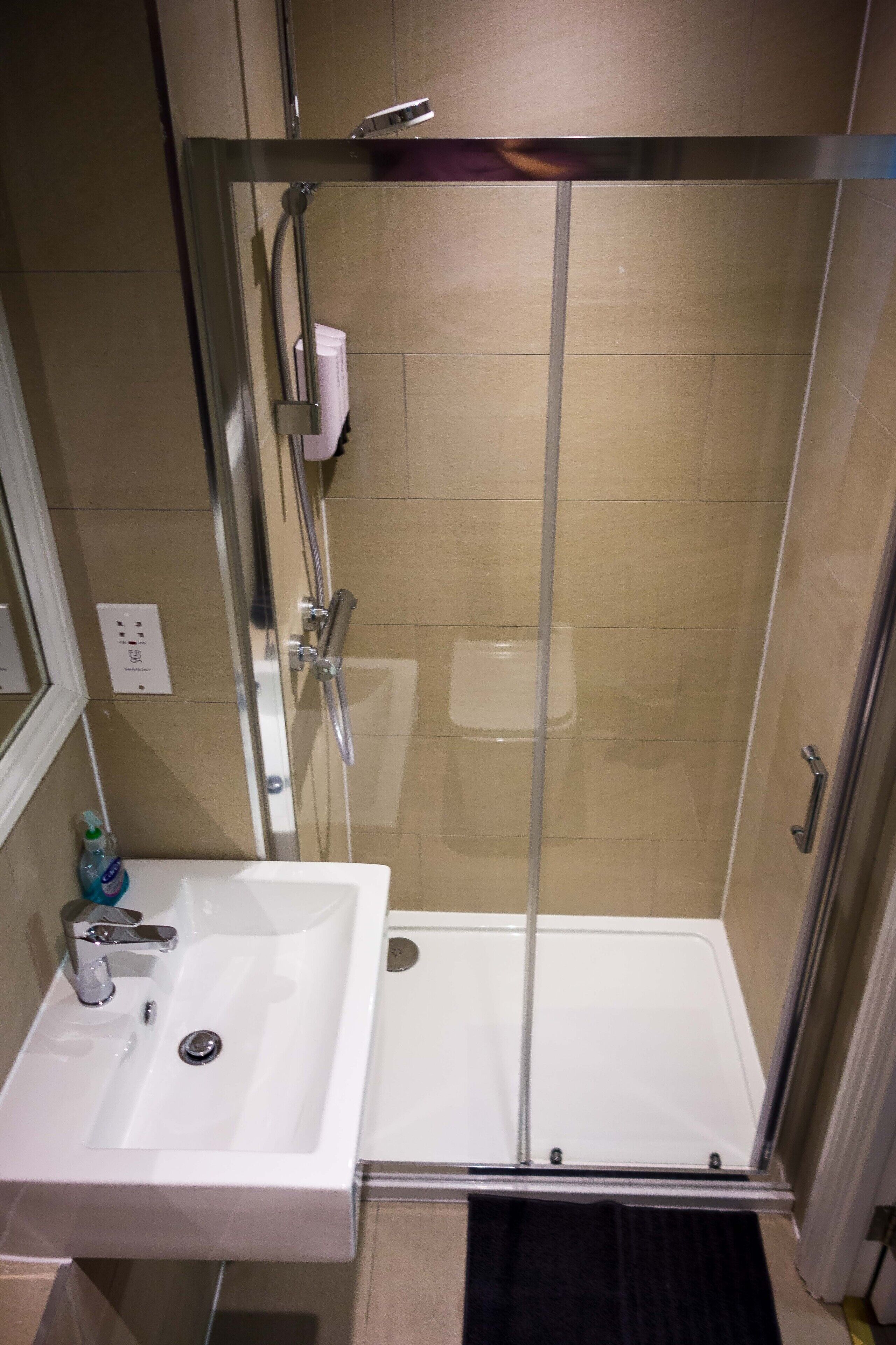 A shower with a glass door, a sink with a mirror, and a toilet.