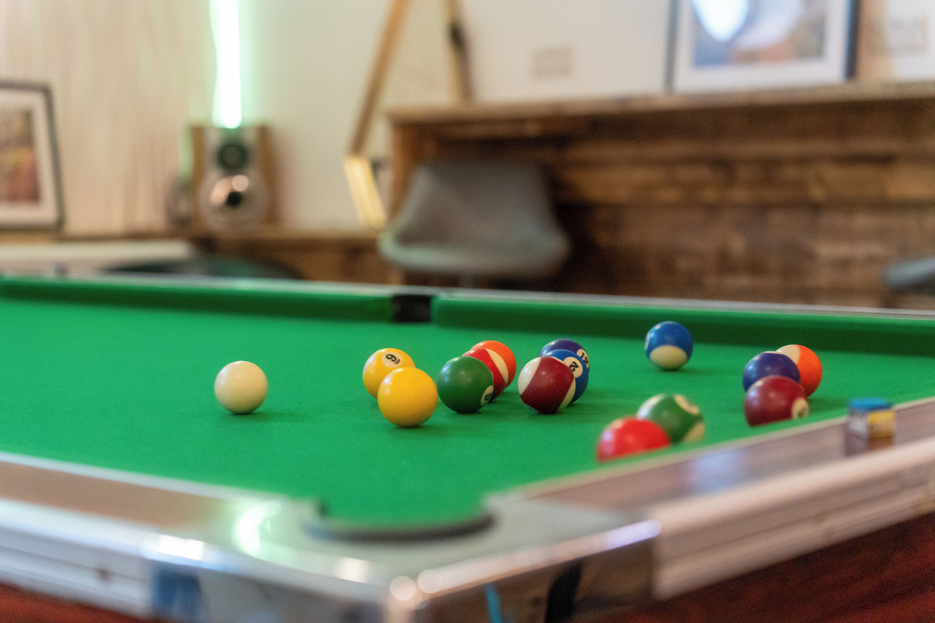 A pool table with various colored balls and a green felt surface.