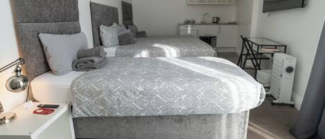 Ein modernes Schlafzimmer mit zwei Betten, einem Schreibtisch und einer Küchenzeile.