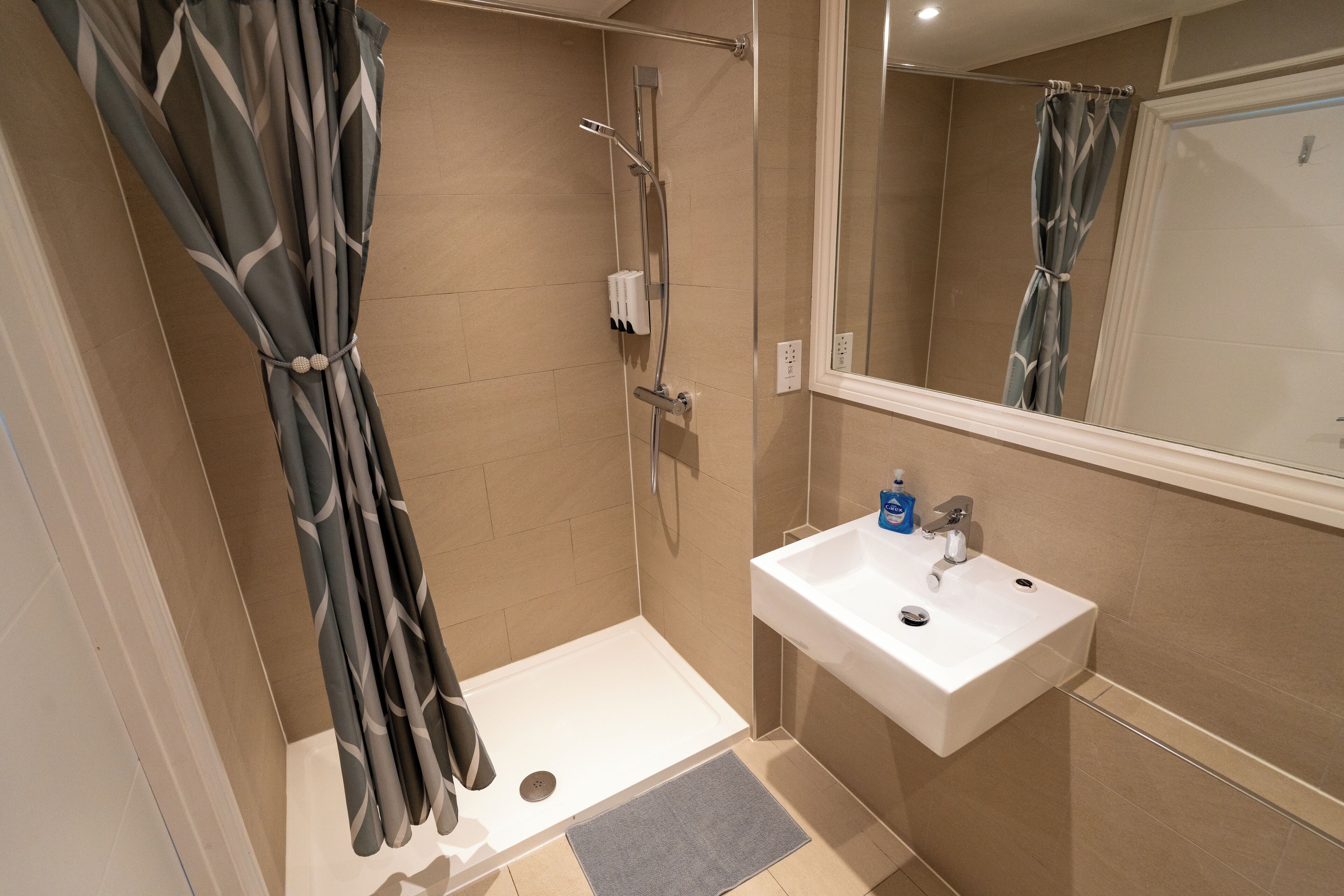 A bathroom with a shower, a sink, and a mirror.
