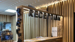Una recepción con mostrador de madera y un cartel que dice 'RECEPTION'.