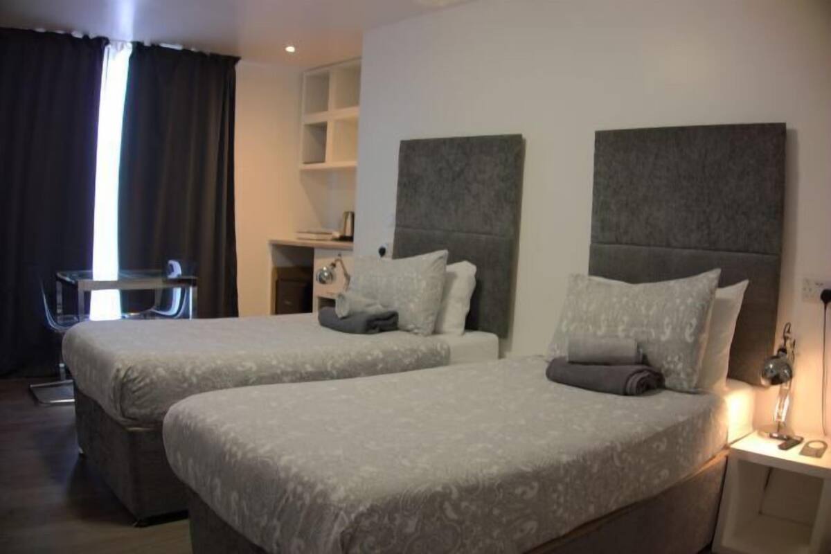 A hotel room with two beds, a desk, and a chair.