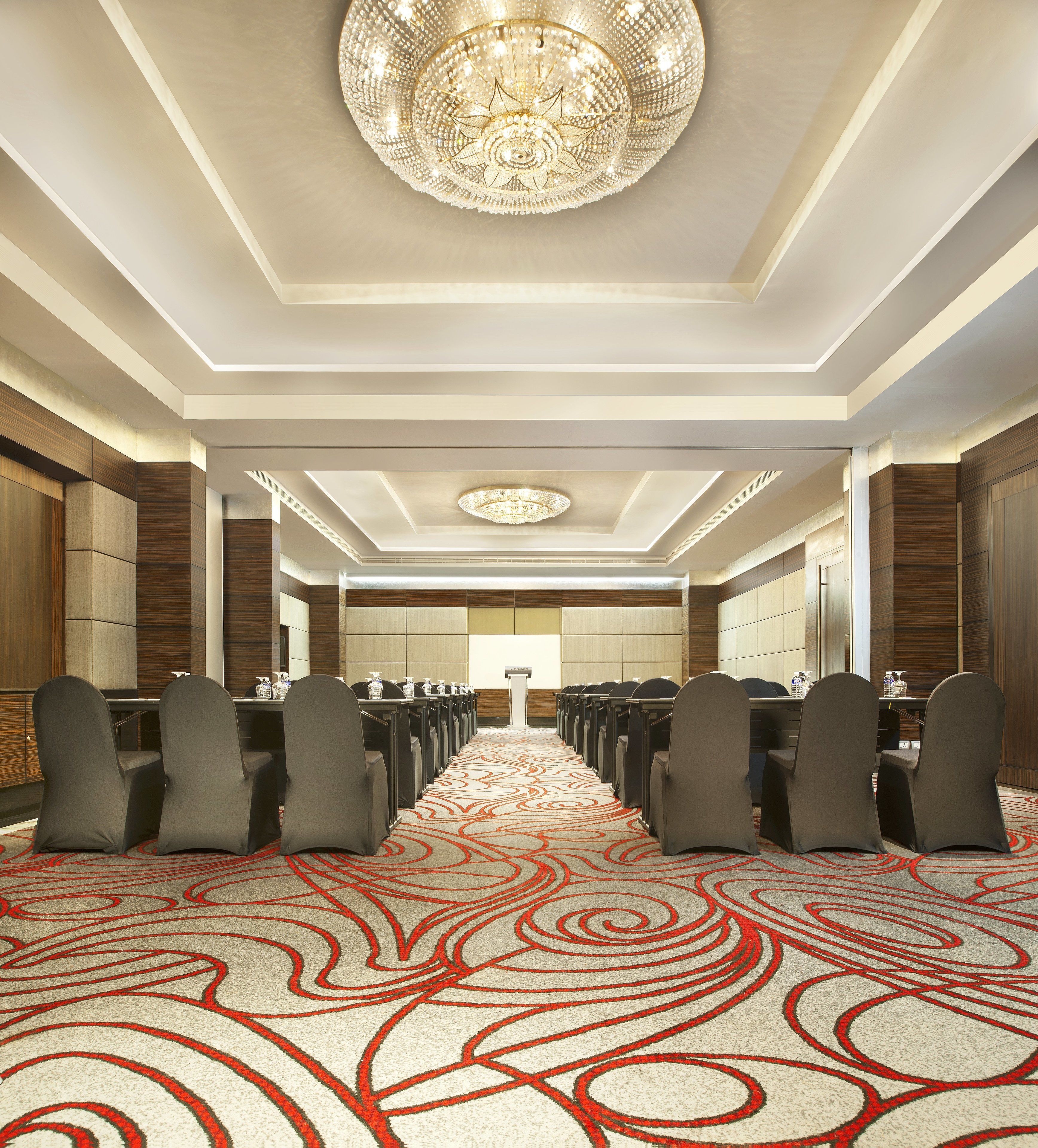 A conference room with rows of chairs, a podium, and a chandelier.