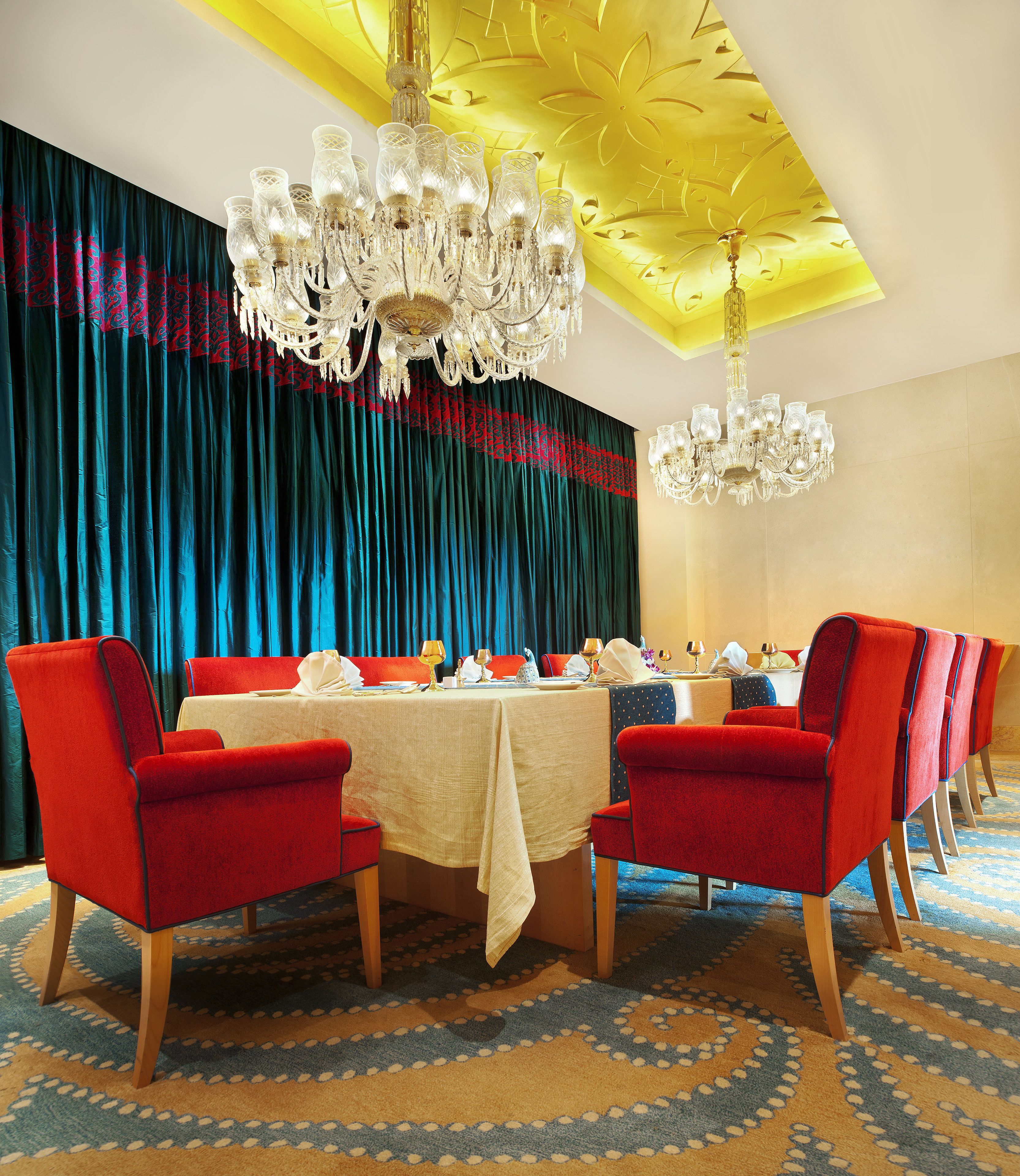 A dining area with a table set for four, surrounded by red upholstered chairs with wooden legs.