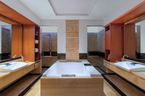 Un baño moderno con dos lavamanos, una bañera grande y muebles de madera.