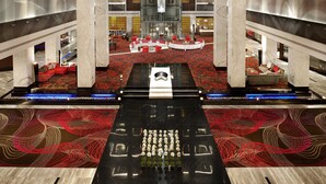 Eine geräumige Lobby mit einem großen Kronleuchter, Marmorsäulen und einem roten Teppichboden.