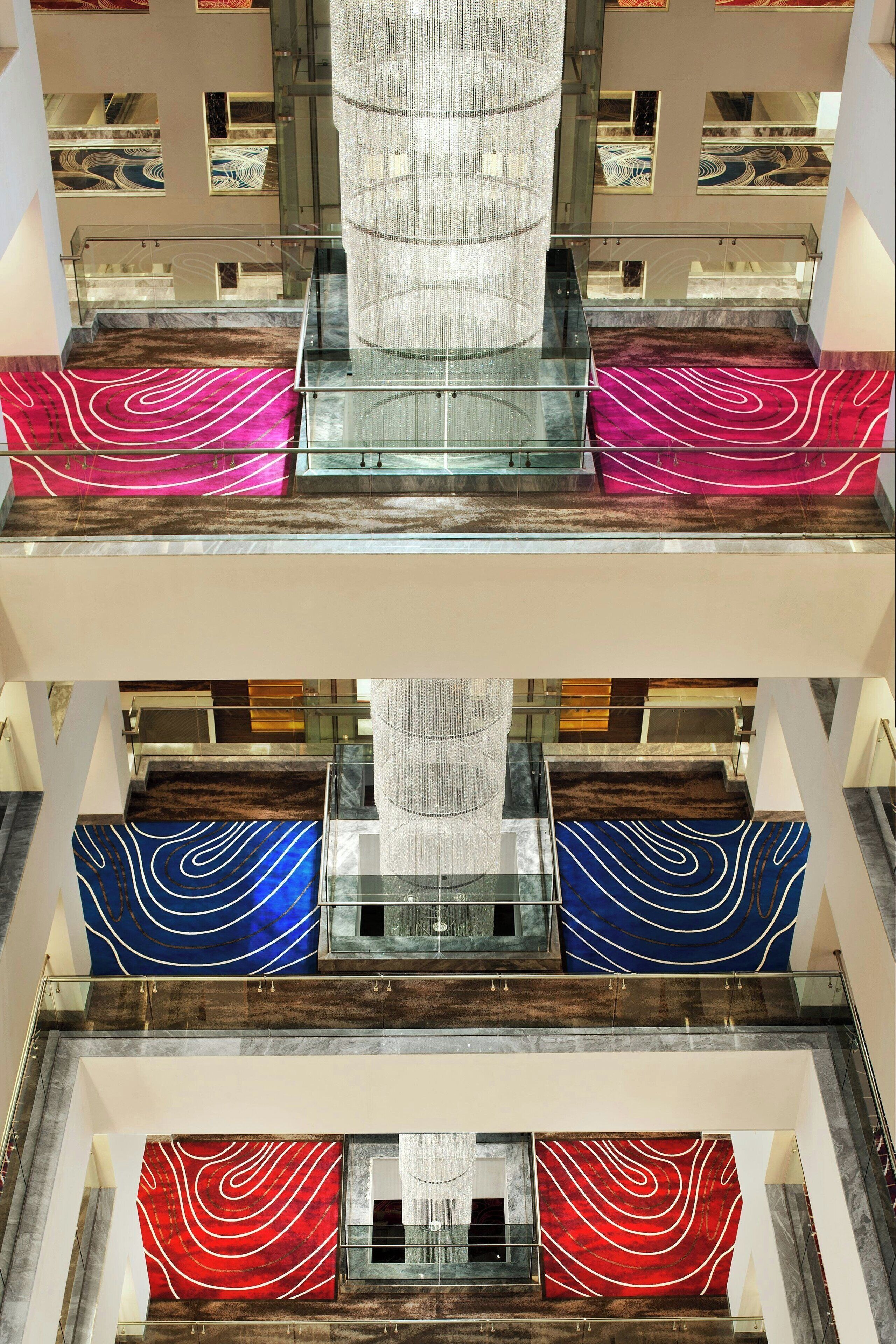 A multi-level interior with glass railings, a central light fixture, and patterned wall panels.
