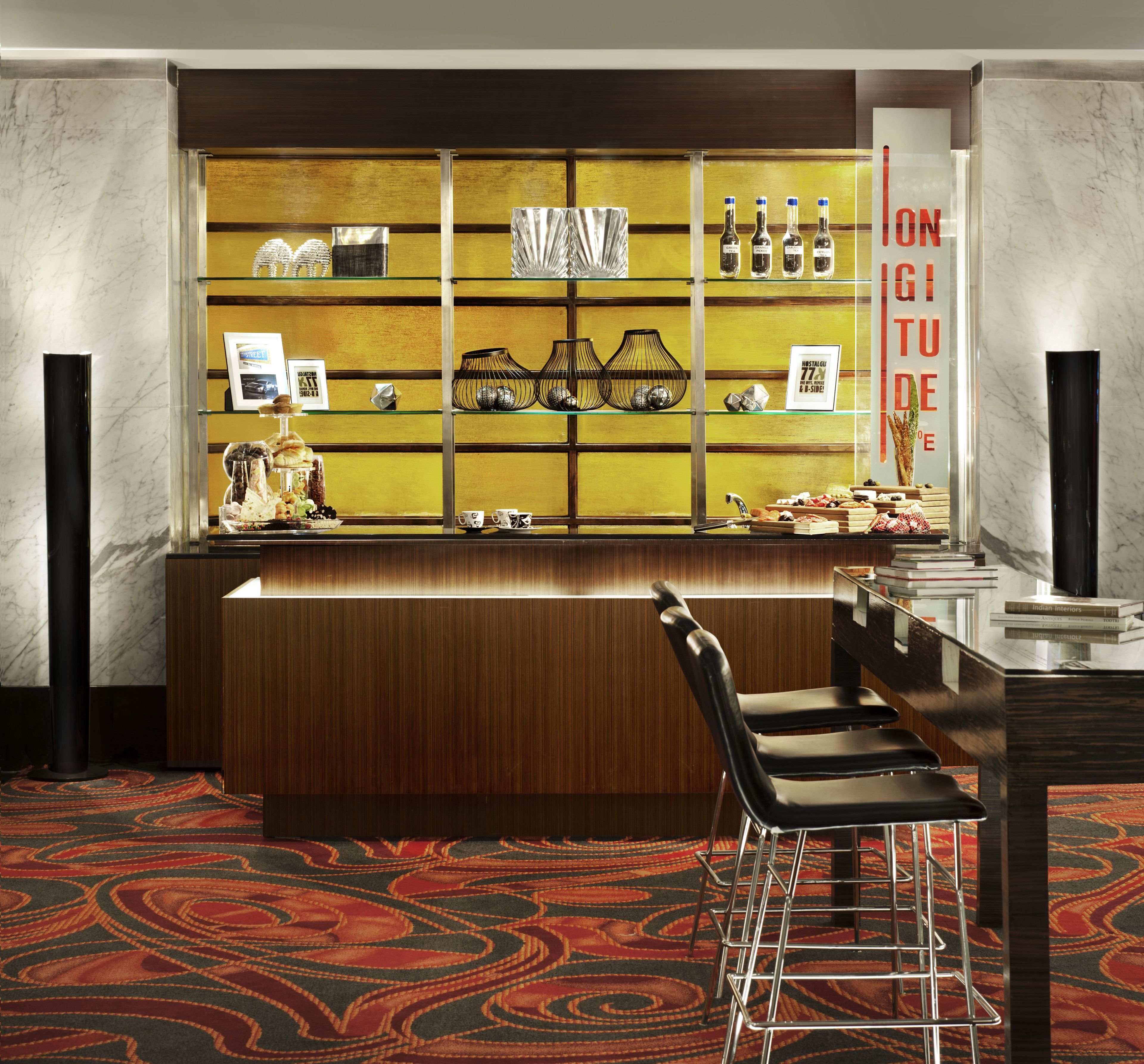 A bar area with a wooden counter, black bar stools, and a patterned carpet.