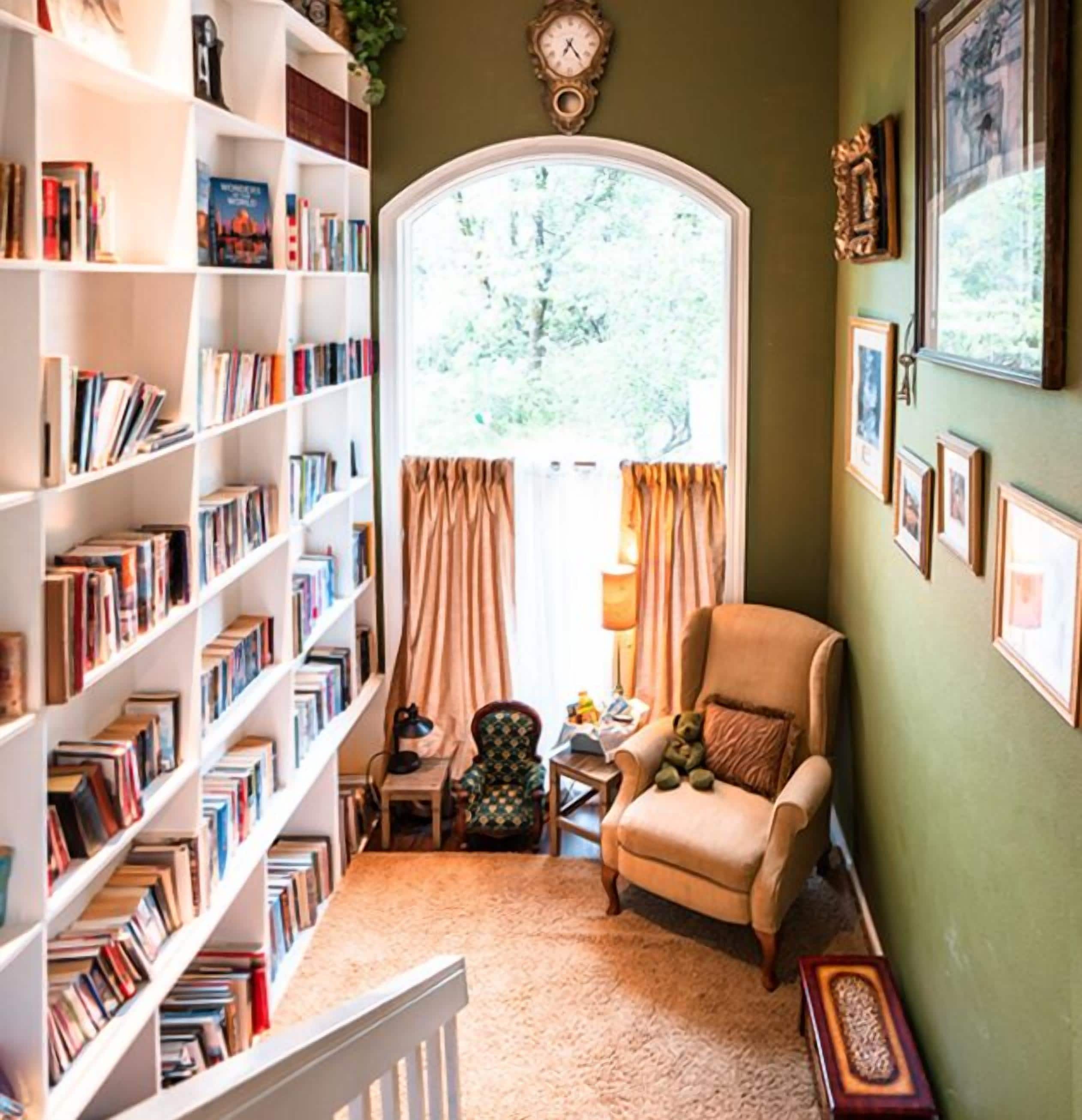 Un rincón acogedor para leer con una estantería, un sillón cómodo y una mesita con una lámpara.