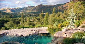 A natural landscape with a clear water body surrounded by rocks and dense forest. - Bella Vista Bed and Breakfast (Placerville)