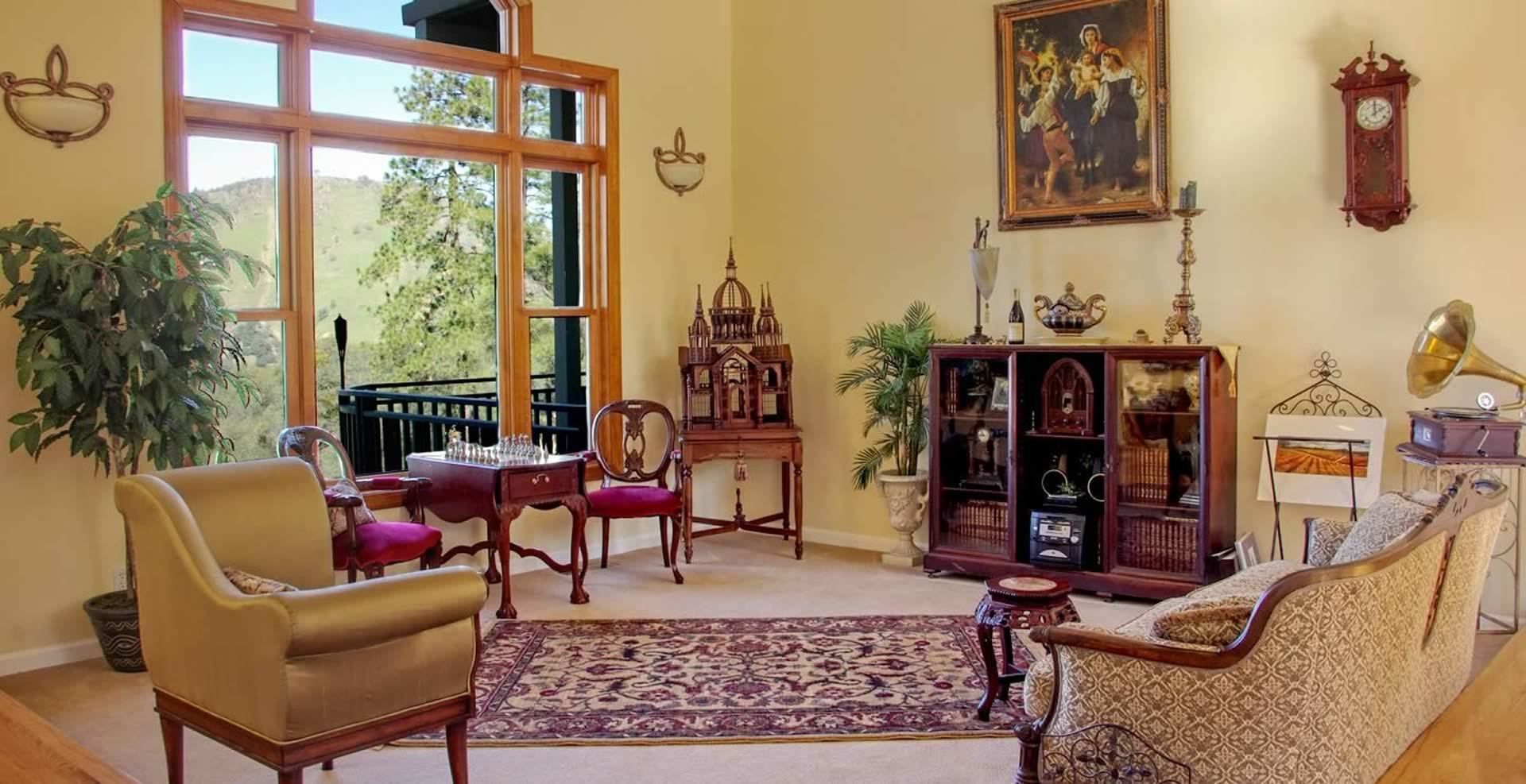 Un salón acogedor con un gran ventanal, un tablero de ajedrez, un piano y un cuadro en la pared.